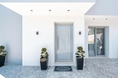 a white hallway with two potted plants and a door at M&B Luxury Villa in Haraki