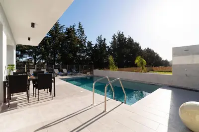 a swimming pool with chairs and a table next to a house at M&B Luxury Villa in Haraki