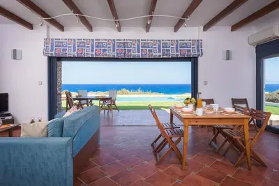 a living room with a blue couch and a table at Cristelia seafront & pool villa in Lachania