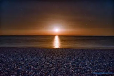 a beach at night with the sun rising over the ocean at Cristelia seafront & pool villa in Lachania