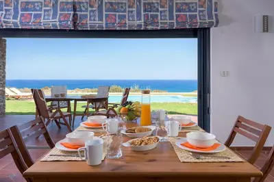 a wooden table with food on it with a view of the ocean at Cristelia seafront & pool villa in Lachania