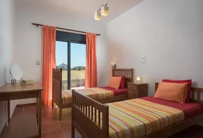 a bedroom with two beds and a desk and a window at Cristelia seafront & pool villa in Lachania