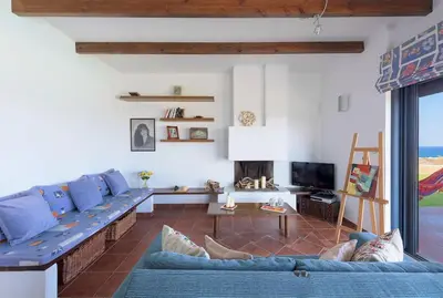 a living room with a blue couch and a tv at Cristelia seafront & pool villa in Lachania