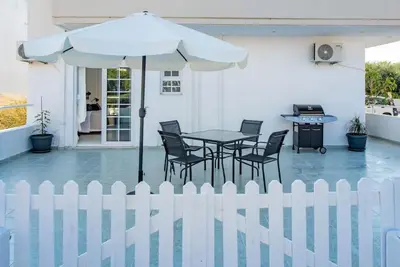 a white fence with a table and chairs and an umbrella at Katris Luxury Homes #1 in Triánta