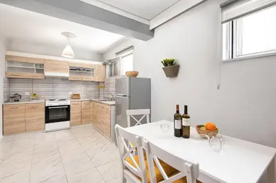 a kitchen with a white table and a refrigerator at Marasi Apartment - Islander's Home Collection in Rhodes Town