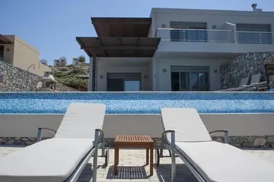 a pair of chairs and a table next to a swimming pool at Pefkos Heights Private Pool Villa in Pefki Rhodes