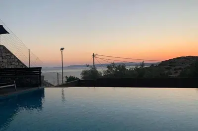 a swimming pool with a sunset in the background at Pefkos Heights Private Pool Villa in Pefki Rhodes
