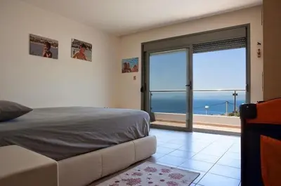 a bedroom with a large window with a view of the ocean at Pefkos Heights Private Pool Villa in Pefki Rhodes