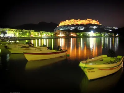three boats sitting in the water at night at Anastasia Beach House Haraki in Rhodes Town