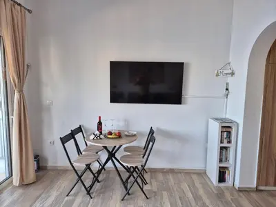 a dining room table with chairs and a television on a wall at Anastasia Beach House Haraki in Rhodes Town