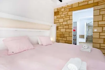 a bedroom with a large white bed with pink pillows at Villa Franky Ladikoheizbarer Pool in Faliraki