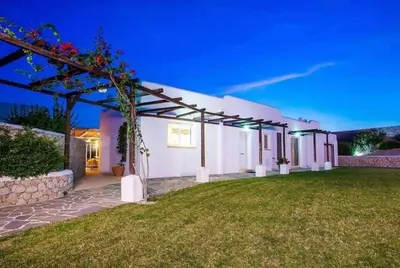 a white house with a green yard at night at Villa Franky Ladikoheizbarer Pool in Faliraki