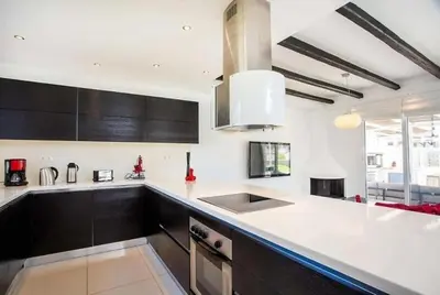 a kitchen with white countertops and black cabinets at Villa Franky Ladikoheizbarer Pool in Faliraki