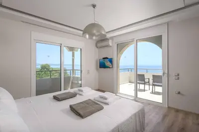 a white bedroom with a bed and a view of the ocean at Paradise Beach I in Kiotari