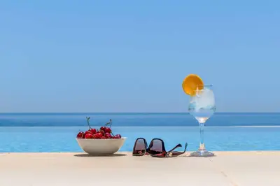 a bowl of fruit and a glass of wine on a beach at Paradise Beach I in Kiotari