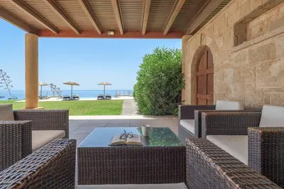 a patio with wicker chairs and a table and the ocean at Paradise Beach I in Kiotari