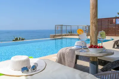 a table with a hat and sunglasses next to a swimming pool at Paradise Beach I in Kiotari
