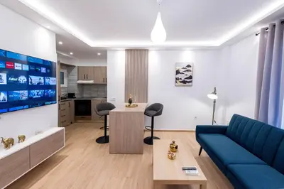 a living room with a blue couch and a kitchen at Hella apartment in Rhodes Town