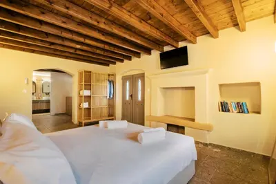 a bedroom with a large white bed and a tv at Rizes Traditional House in Phanaes