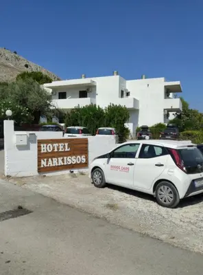 a white car parked next to a hotel sign at Hotel Narkissos in Archangelos