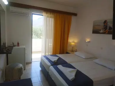 a hotel room with two beds and a large window at Hotel Narkissos in Archangelos