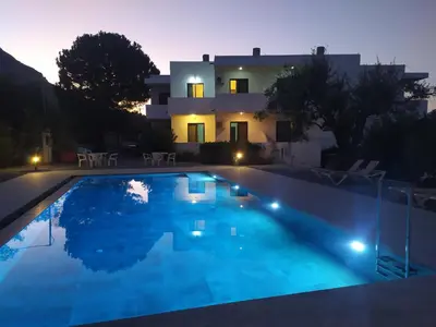 a villa with a swimming pool at night at Hotel Narkissos in Archangelos
