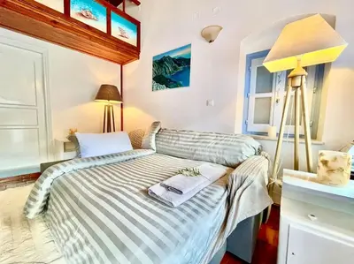 a small bedroom with a bed and a lamp at Nikolakis, Seafront- Harbor view in Symi