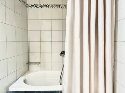 a bath tub with a shower curtain in a bathroom at Nikolakis, Seafront- Harbor view in Symi