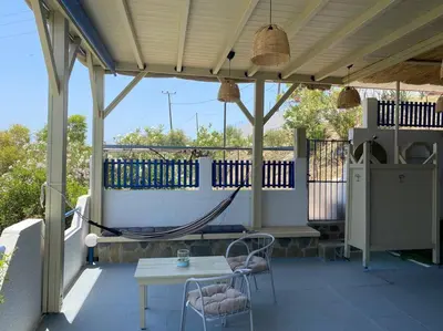 a porch with a hammock and a table and chairs at Sylvia's Beach House in Stegna in Archangelos