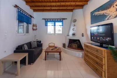 a living room with a tv and a couch and a fireplace at Sylvia's Beach House in Stegna in Archangelos