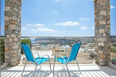 two chairs and a table on a balcony with a view at Villa Karma Lindos in Líndos