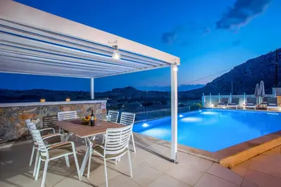 a patio with a table and chairs next to a swimming pool at Villa Karma Lindos in Líndos