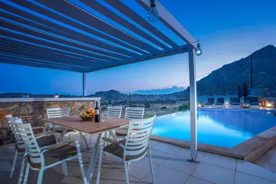 a patio with a table and chairs and a pool at Villa Karma Lindos in Líndos