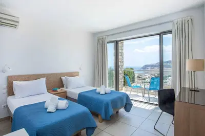 a hotel room with two beds and a balcony at Villa Karma Lindos in Líndos