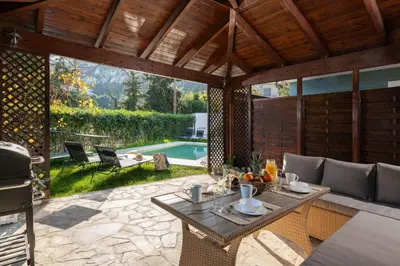 a patio with a table and chairs and a pool at Villa Annatoli in Koskinou
