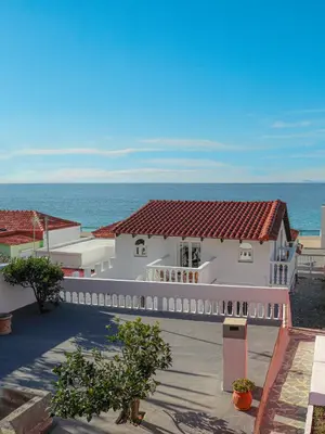 a large white house with the ocean in the background at Angels beach house in Rhodes Town