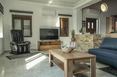 a living room with a blue couch and a tv at Angels beach house in Rhodes Town