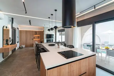an open kitchen with a large island and a dining room at Villa Palmeras Evelia by Villa Plus in Ialyssos