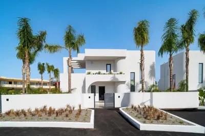 a white house with palm trees in front of it at Villa Palmeras Evelia by Villa Plus in Ialyssos