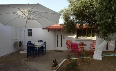 a white house with a table and chairs and an umbrella at Nadia's House 2 in Afantou