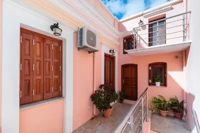 a facade of a house with wooden doors and potted plants at YIAYIA's Central Apartment in Symi