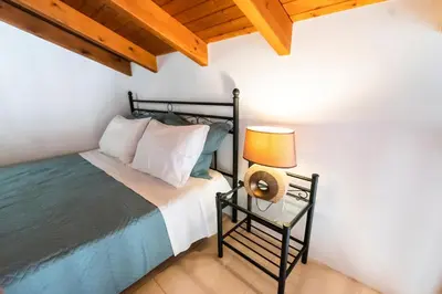 a bedroom with a bed and a lamp on a table at YIAYIA's Central Apartment in Symi
