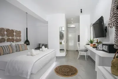 a white bedroom with a bed and a tv at Calma Luxury Studios & Suites in Faliraki
