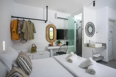 a bedroom with a bed and a sink and a mirror at Calma Luxury Studios & Suites in Faliraki