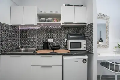 a kitchen with white cabinets and a microwave at Calma Luxury Studios & Suites in Faliraki
