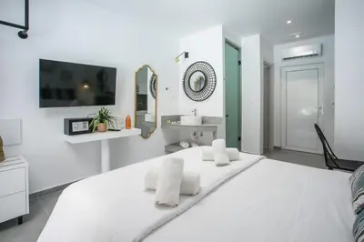 a white bedroom with a large bed and a sink at Calma Luxury Studios & Suites in Faliraki