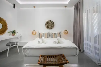 a white bedroom with a bed and a table at Calma Luxury Studios & Suites in Faliraki