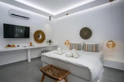 a white bedroom with a bed and a tv at Calma Luxury Studios & Suites in Faliraki