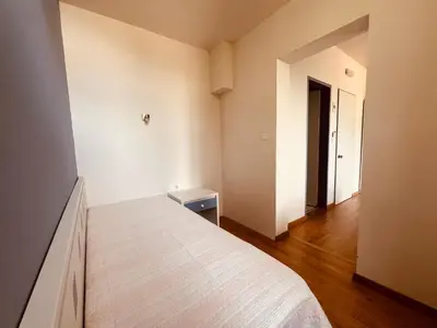 a white bedroom with a bed and a hallway at Maistrali Hotel & Restaurant in Kalavárda