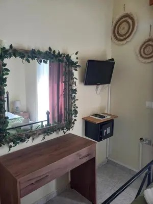a mirror in a room with a desk and a tv at Maria's garden house in Archangelos